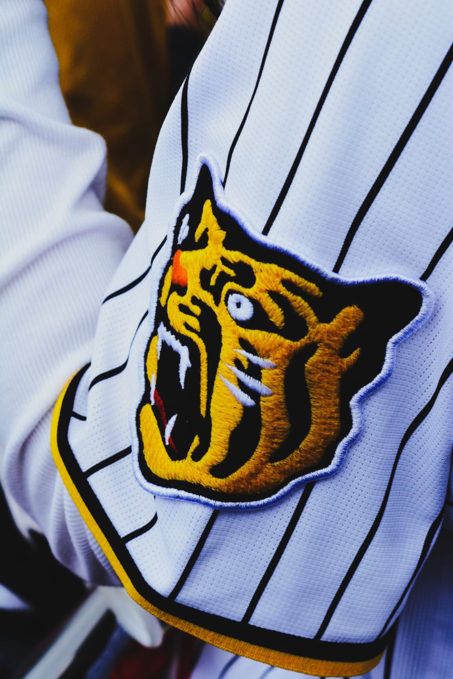 Embroidered tiger crest stitched onto the sleeve of a pinstriped team jersey