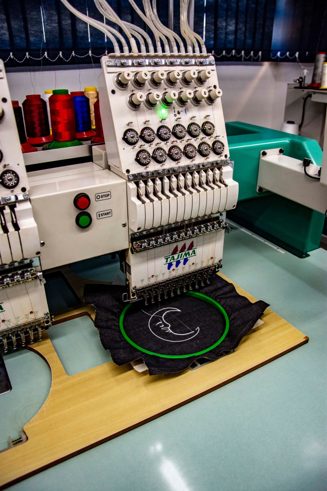 Multi-head embroidery machine stitching a logo into a hooped garment