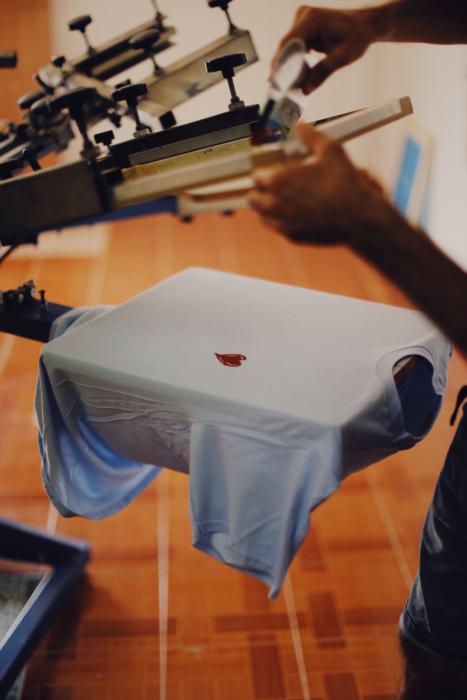 Press operator laying a printed transfer onto a shirt in the workroom