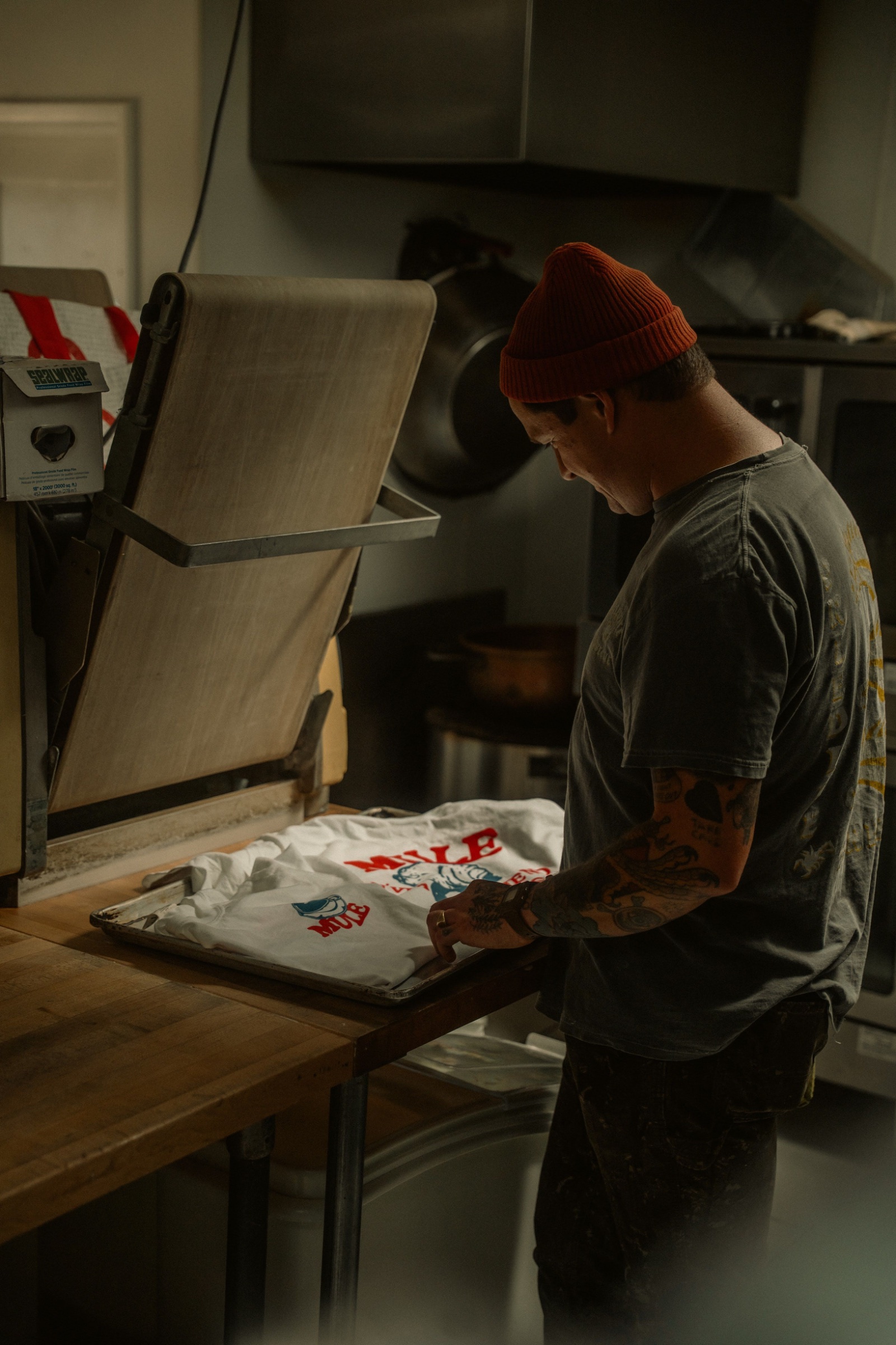 Screen printer pulling ink across a tee on the press platen